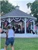 A band playing in the gazebo with a woman dancing