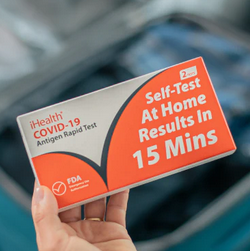 a hand holding an iHealth covid-19 test kit