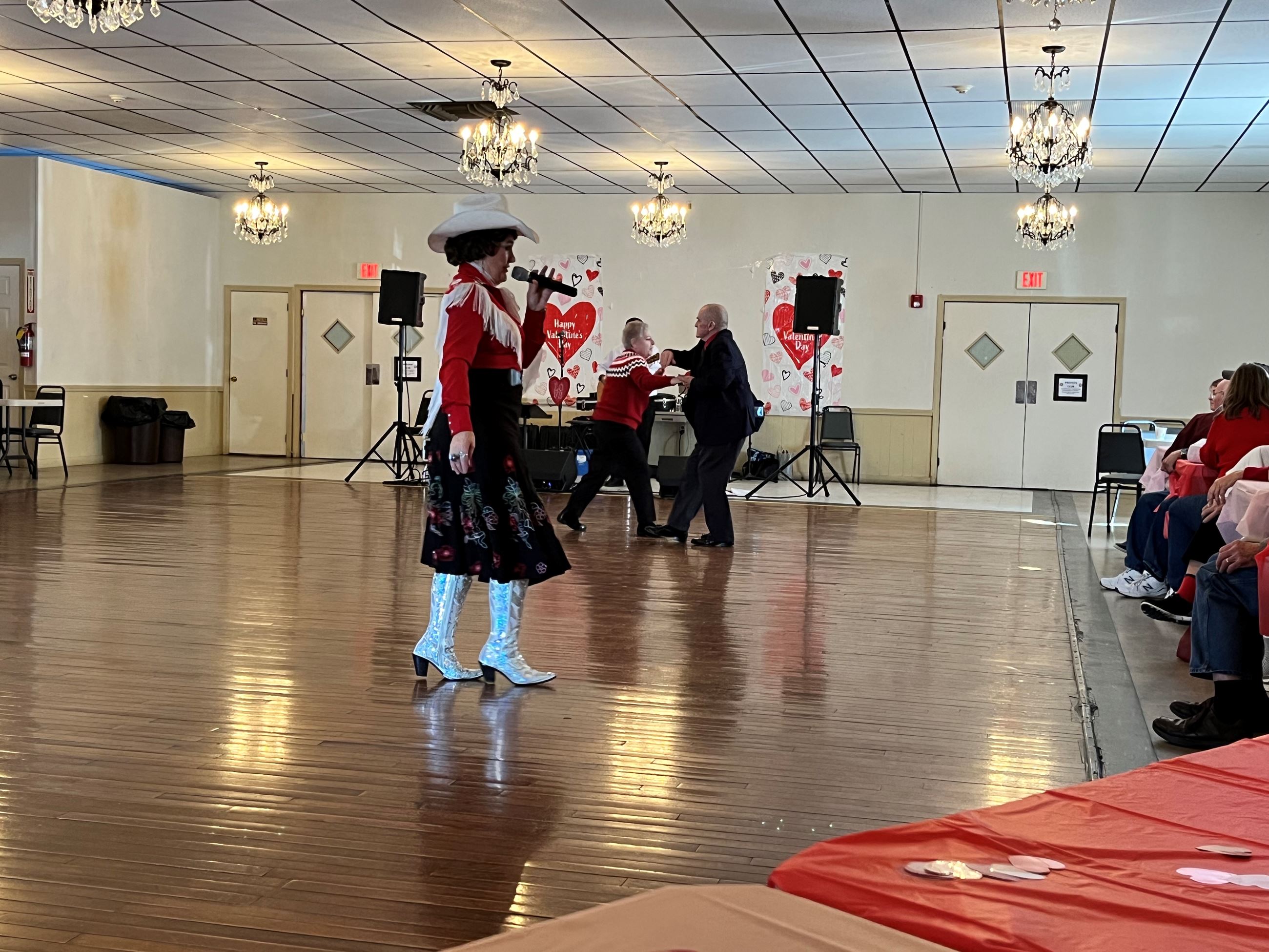A woman with a microphone and a couple dancing