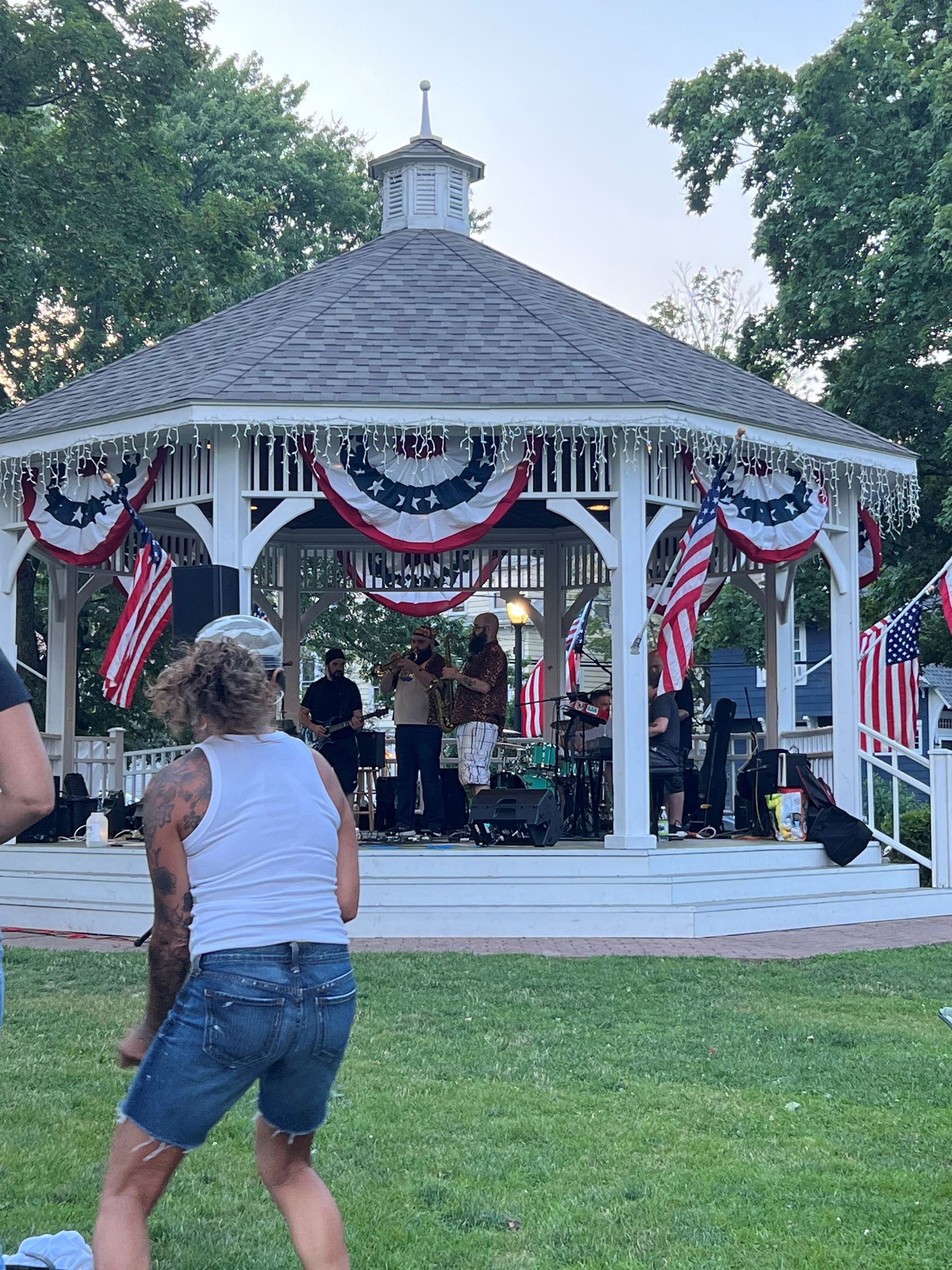 A band playing in the gazebo with a woman dancing