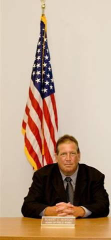 Photo of Robert C. Norton the once Chairman of the Board of Public Works, sitting at a table.